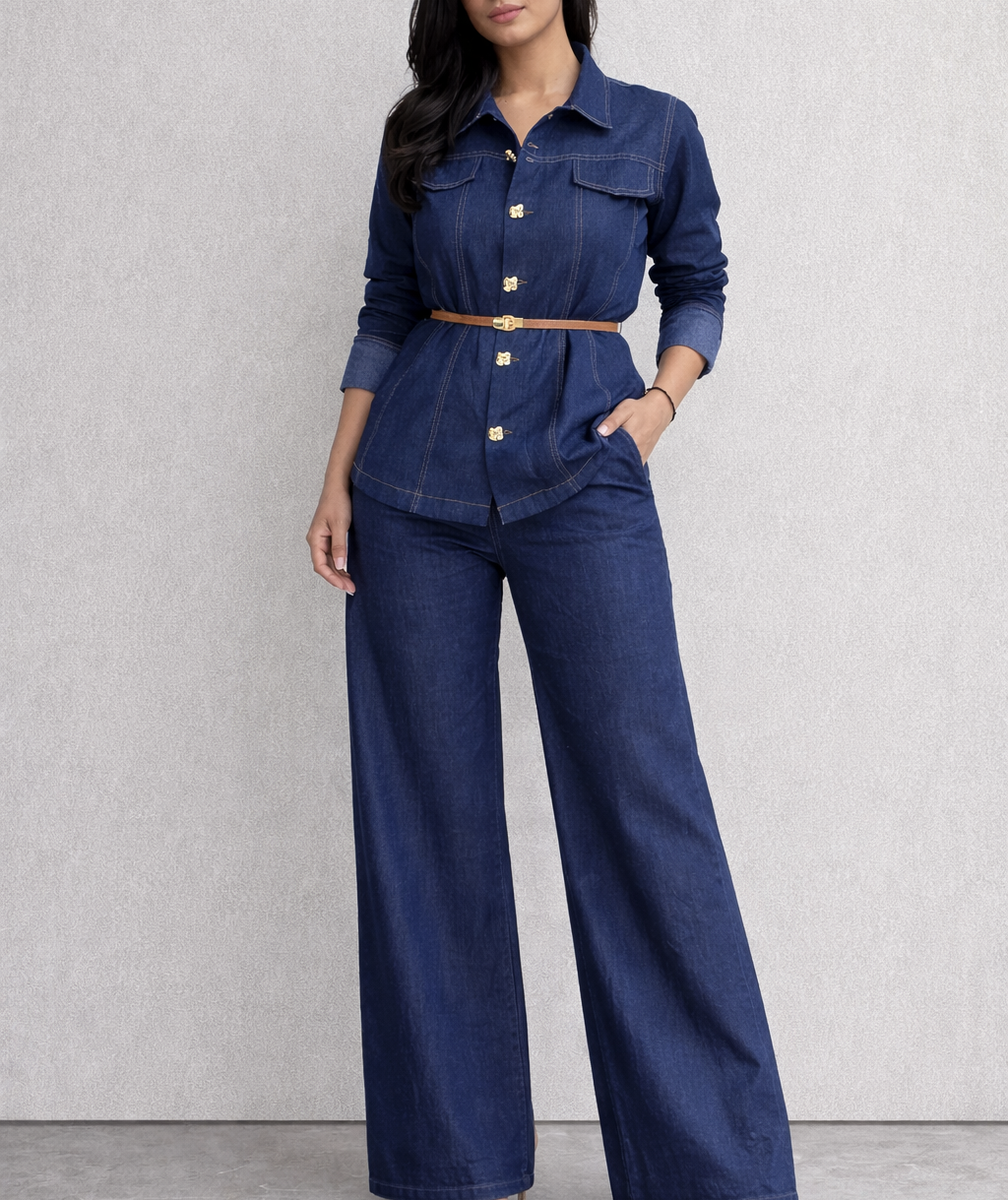 Woman wearing a blue denim outfit with a belt against a light gray background