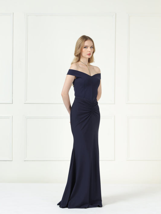 Woman wearing a navy off-shoulder gown against a white background